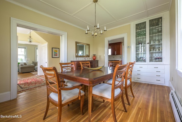 dining space with an inviting chandelier, ornamental molding, baseboard heating, and wood finished floors
