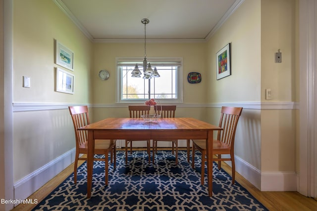 dining area featuring baseboards, ornamental molding, an inviting chandelier, and wood finished floors