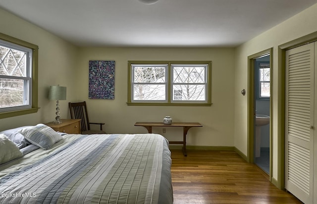 bedroom featuring dark wood-type flooring, a closet, and multiple windows