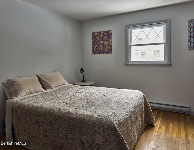 bedroom with wood-type flooring and a baseboard heating unit