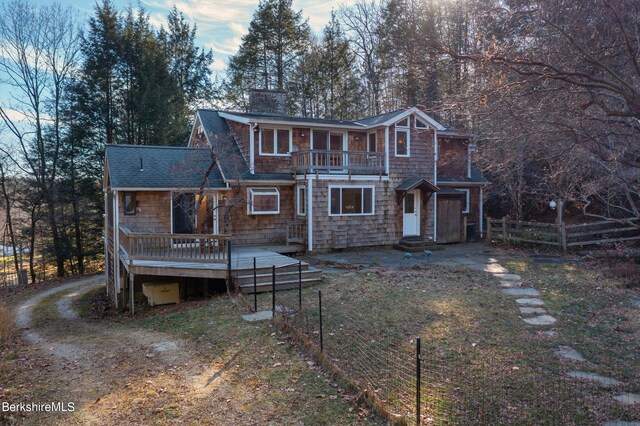 rear view of house featuring a lawn and a deck