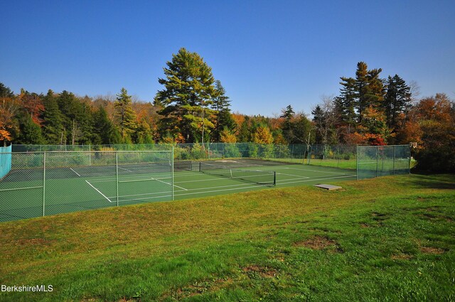 view of sport court with a lawn and fence