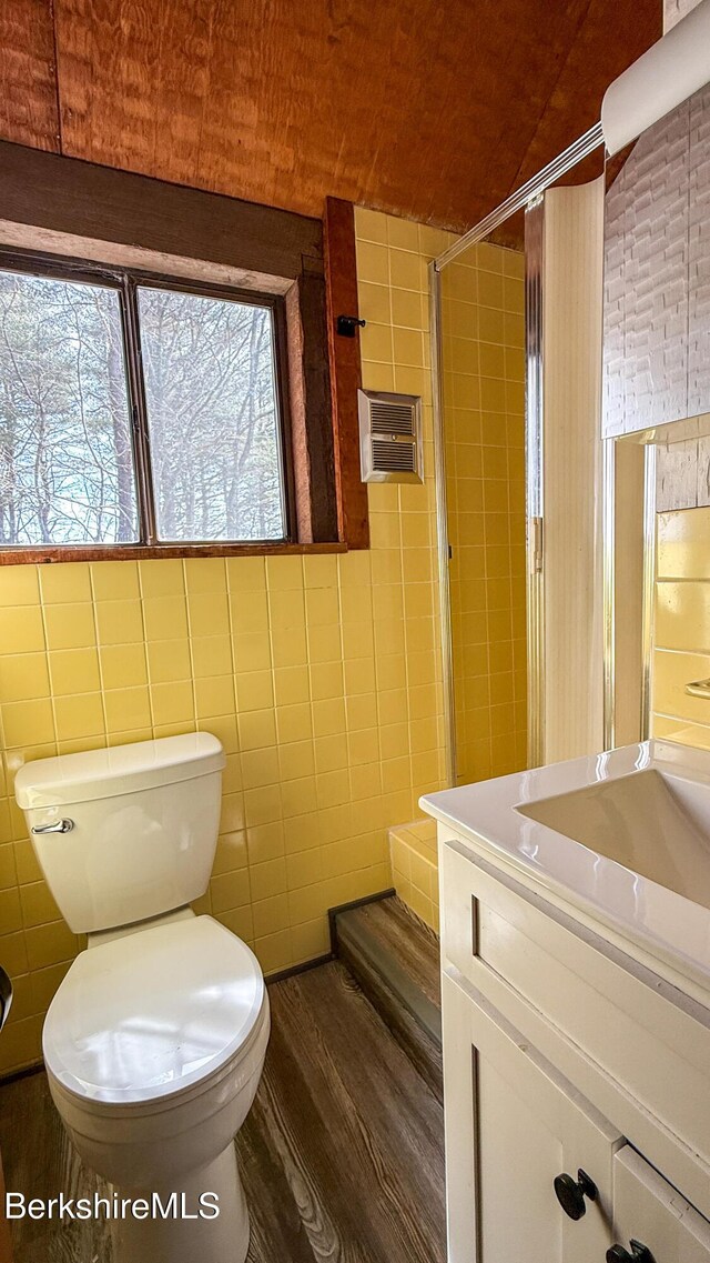 bathroom with toilet, a wall mounted AC, wood finished floors, tile walls, and vanity