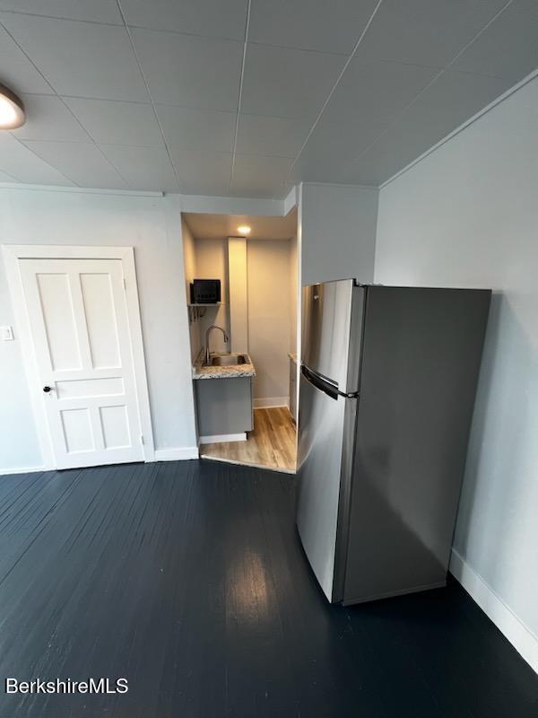 kitchen featuring dark wood-style floors, baseboards, light countertops, and freestanding refrigerator