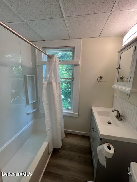 full bathroom with shower / tub combo, a drop ceiling, wood finished floors, and vanity