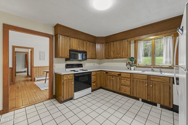 64 Blotz Rd, Washington, MA 01223 - kitchen with black microwave, range with electric cooktop, baseboard heating, a sink, and brown cabinets
