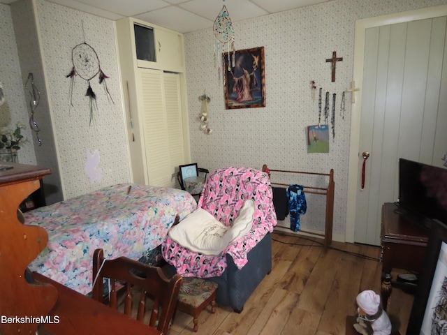 bedroom featuring a paneled ceiling, a closet, and hardwood / wood-style floors