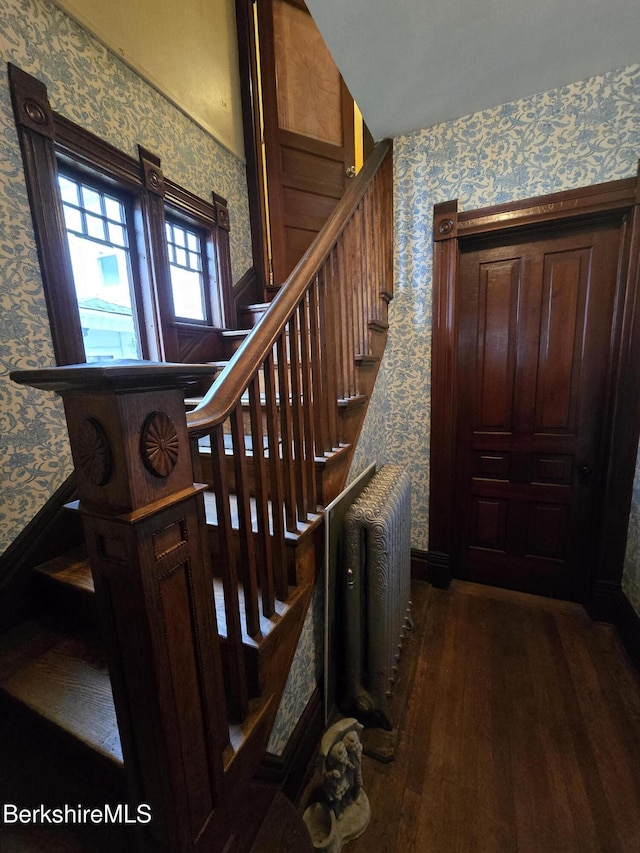 stairway with radiator and hardwood / wood-style flooring