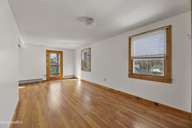 unfurnished room featuring wood finished floors, baseboards, baseboard heating, and a baseboard radiator