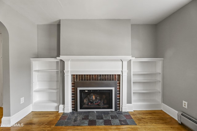 details featuring a fireplace with flush hearth, wood finished floors, arched walkways, and baseboard heating