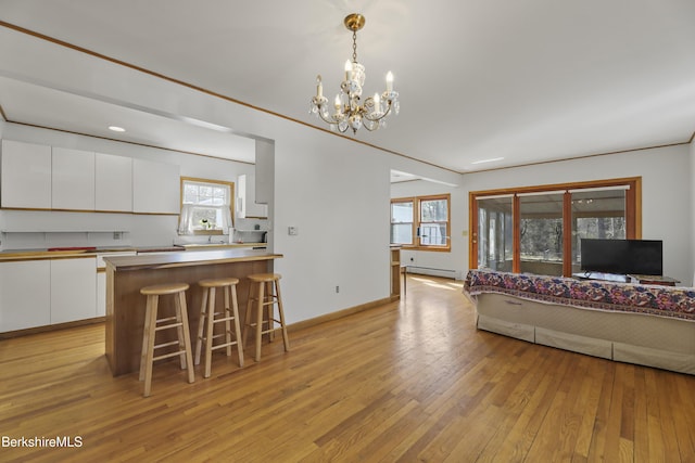 interior space featuring light wood-type flooring, a baseboard heating unit, baseboards, and an inviting chandelier