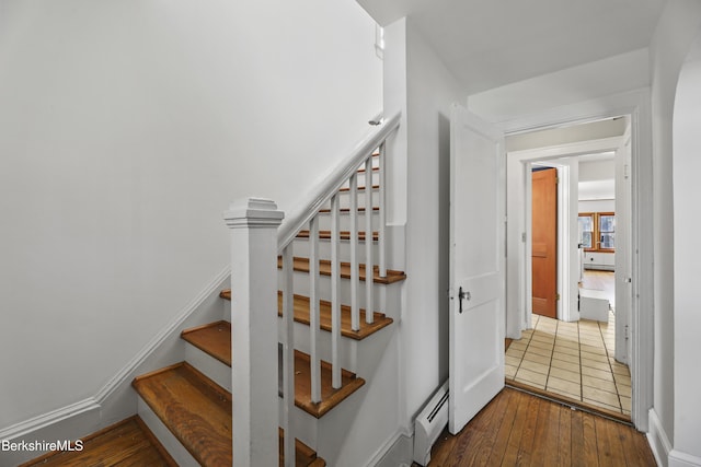 stairway featuring hardwood / wood-style floors, baseboards, and a baseboard radiator