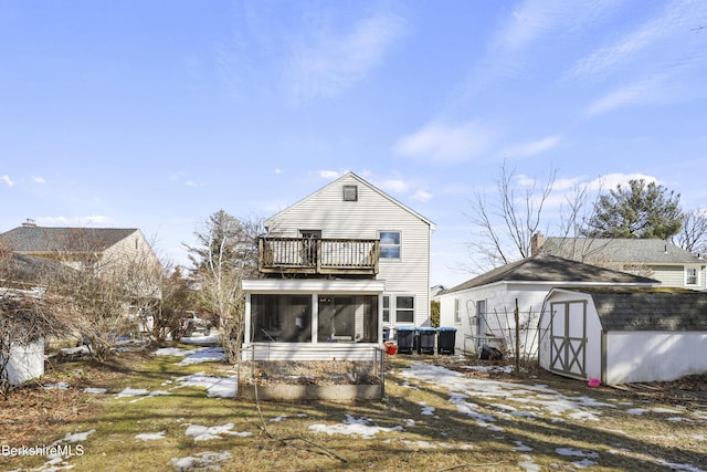 back of property with a sunroom, a balcony, an outdoor structure, and a shed