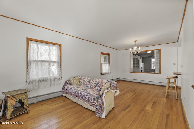 living room with a notable chandelier, baseboard heating, hardwood / wood-style floors, and crown molding