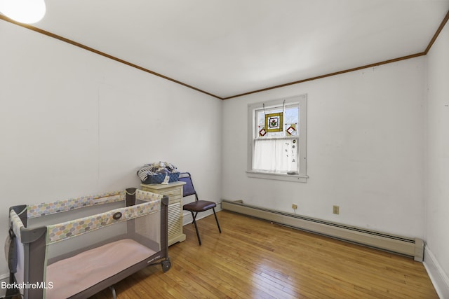 sitting room featuring a baseboard heating unit, wood-type flooring, and ornamental molding