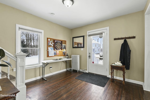 foyer entrance with radiator, baseboards, and dark wood-type flooring