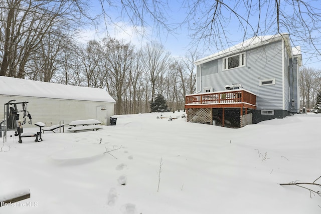 snow covered property featuring a garage and a wooden deck