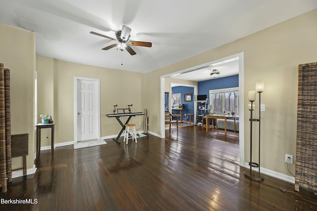 spare room featuring dark wood-type flooring, radiator, ceiling fan, and baseboards