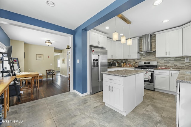 kitchen with pendant lighting, wall chimney exhaust hood, white cabinets, and stainless steel appliances