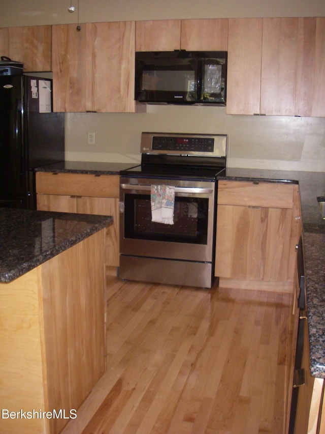 kitchen featuring black appliances, light hardwood / wood-style floors, and dark stone countertops