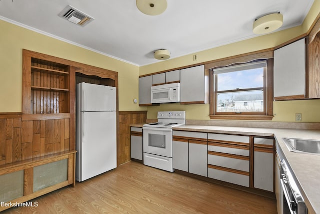 kitchen featuring light wood finished floors, visible vents, crown molding, light countertops, and white appliances