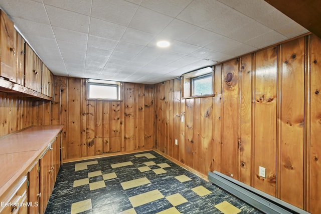 below grade area featuring wooden walls, dark floors, and a baseboard radiator