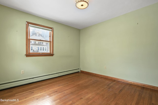 empty room with hardwood / wood-style flooring, baseboards, and a baseboard radiator