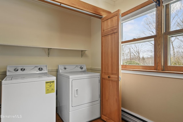 clothes washing area with a wealth of natural light, a baseboard radiator, separate washer and dryer, and laundry area