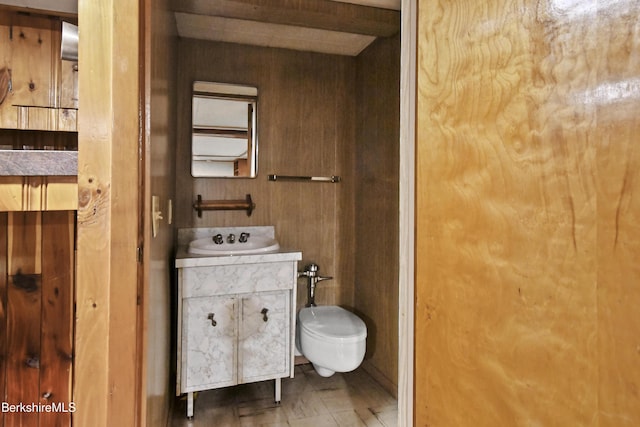 bathroom featuring beamed ceiling, wood walls, toilet, and vanity