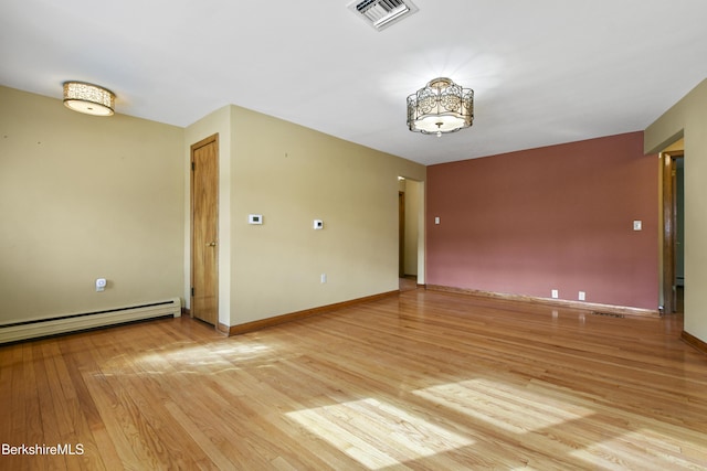 unfurnished room featuring a baseboard heating unit, light wood-style flooring, baseboards, and visible vents