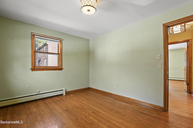 unfurnished room featuring baseboards, baseboard heating, and hardwood / wood-style flooring