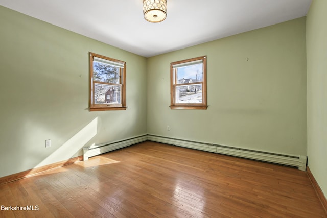 spare room with a baseboard radiator, wood-type flooring, and baseboards