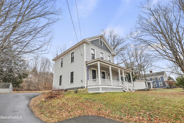 view of property exterior featuring covered porch and a lawn