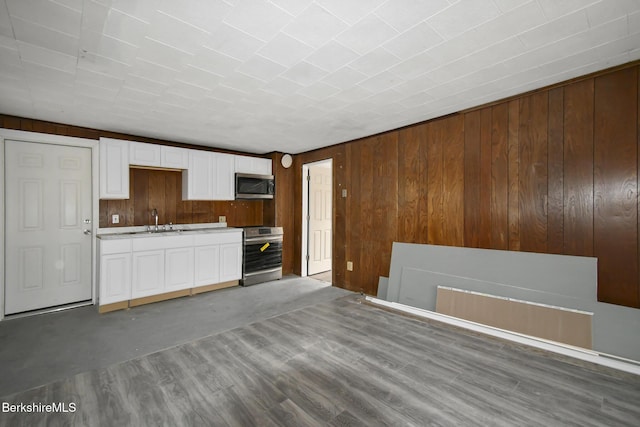 111 Columbia St, Adams, MA 01220 - kitchen with light countertops, white cabinetry, wood walls, stainless steel appliances, and a sink