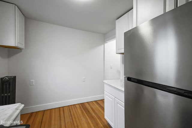 111 Columbia St, Adams, MA 01220 - kitchen featuring baseboards, light wood-style flooring, freestanding refrigerator, white cabinets, and radiator