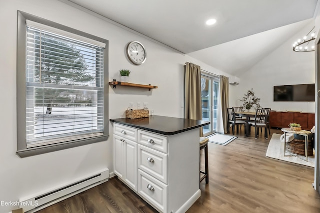 kitchen featuring dark wood-type flooring, baseboard heating, a kitchen breakfast bar, white cabinets, and kitchen peninsula