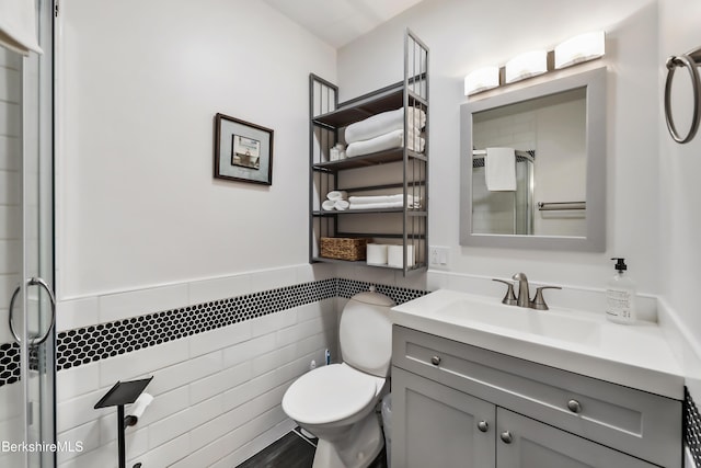 bathroom featuring tile walls, vanity, a shower with door, and toilet