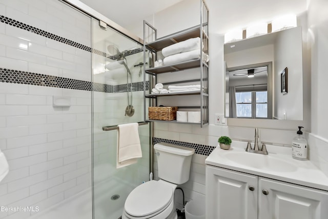 bathroom with toilet, a shower with shower door, tile walls, vanity, and decorative backsplash