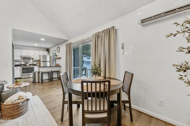 dining space with lofted ceiling, light hardwood / wood-style flooring, and an AC wall unit