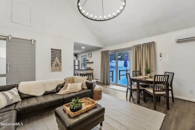 living room featuring an AC wall unit, high vaulted ceiling, dark hardwood / wood-style flooring, a notable chandelier, and a barn door