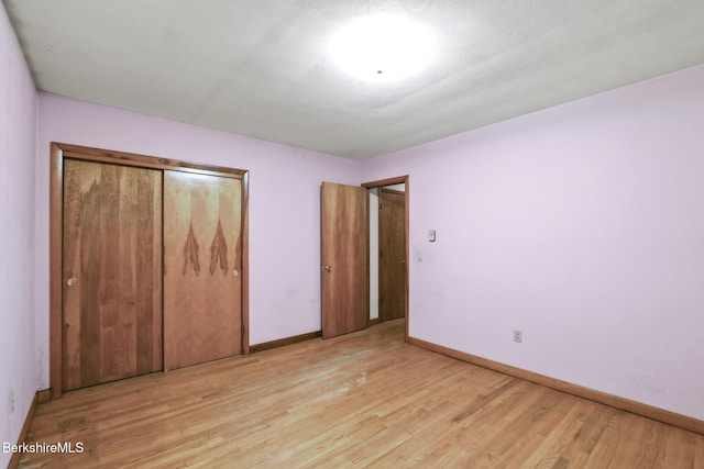 unfurnished bedroom with light wood-type flooring and a closet