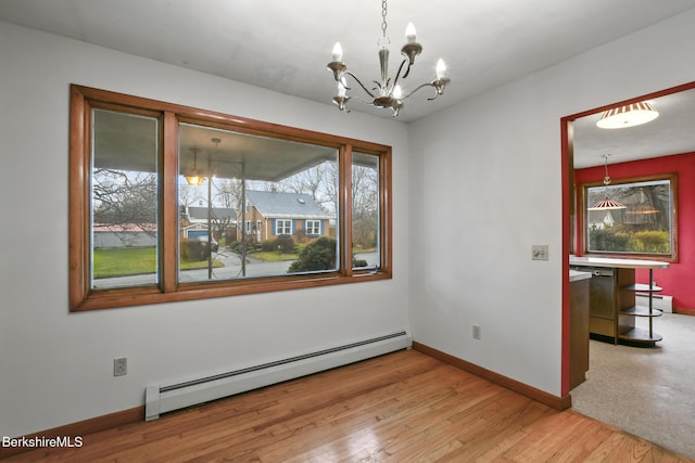 unfurnished dining area with light hardwood / wood-style flooring, baseboard heating, and an inviting chandelier