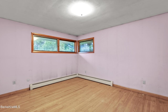 unfurnished room featuring a baseboard radiator and light hardwood / wood-style flooring