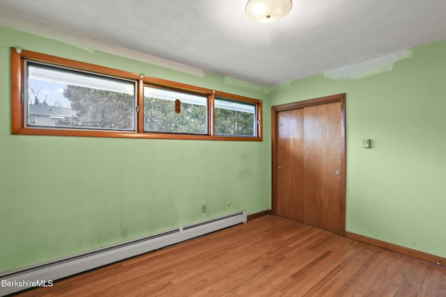 unfurnished bedroom featuring a closet, light hardwood / wood-style flooring, and a baseboard heating unit