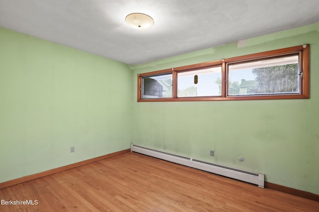 empty room featuring light hardwood / wood-style floors and a baseboard heating unit