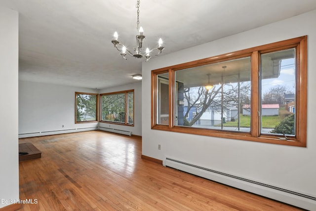 unfurnished room with light hardwood / wood-style floors, baseboard heating, and a chandelier