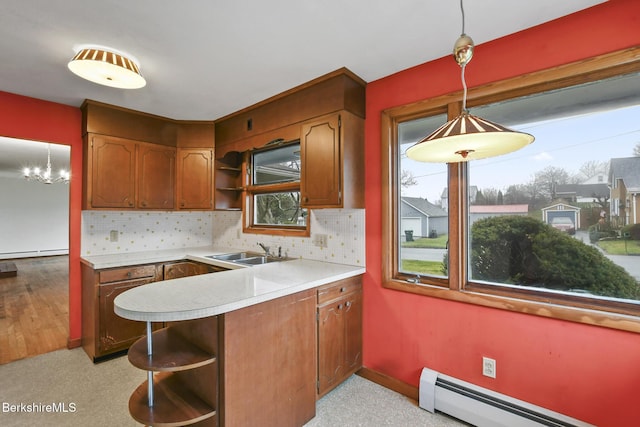 kitchen with decorative backsplash, pendant lighting, baseboard heating, and sink