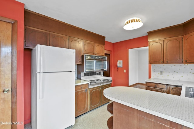 kitchen with tasteful backsplash, kitchen peninsula, and white appliances