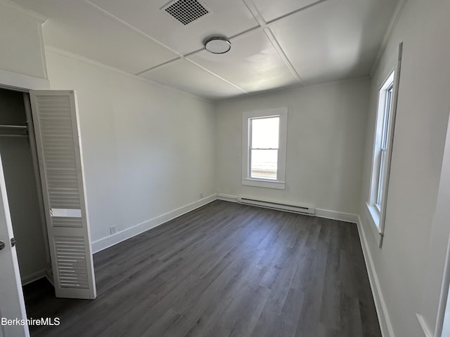 unfurnished bedroom with dark wood-type flooring, a closet, and baseboard heating