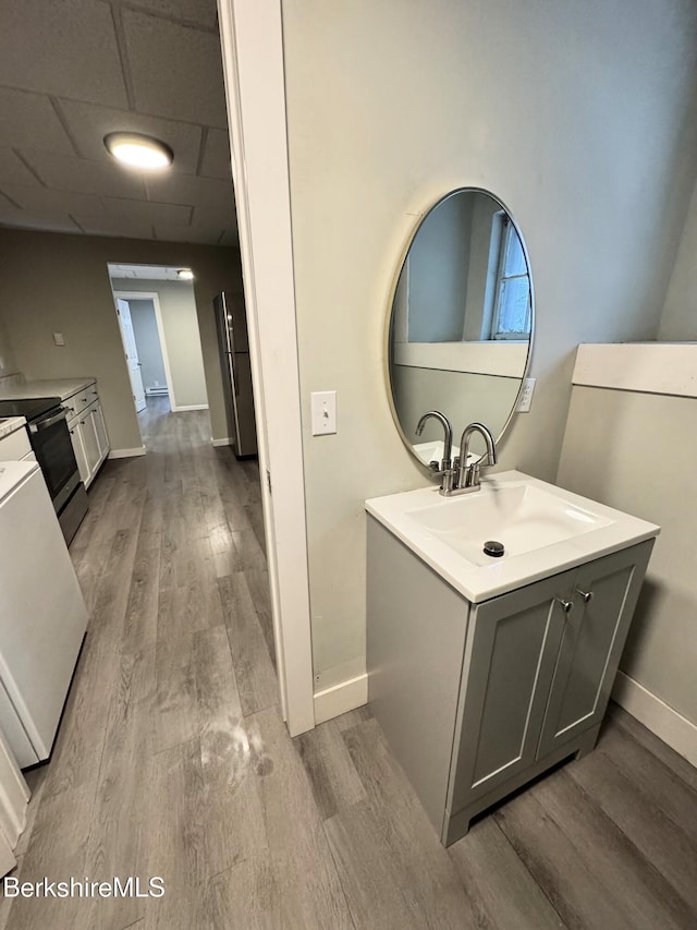 bathroom with a drop ceiling, hardwood / wood-style floors, and vanity